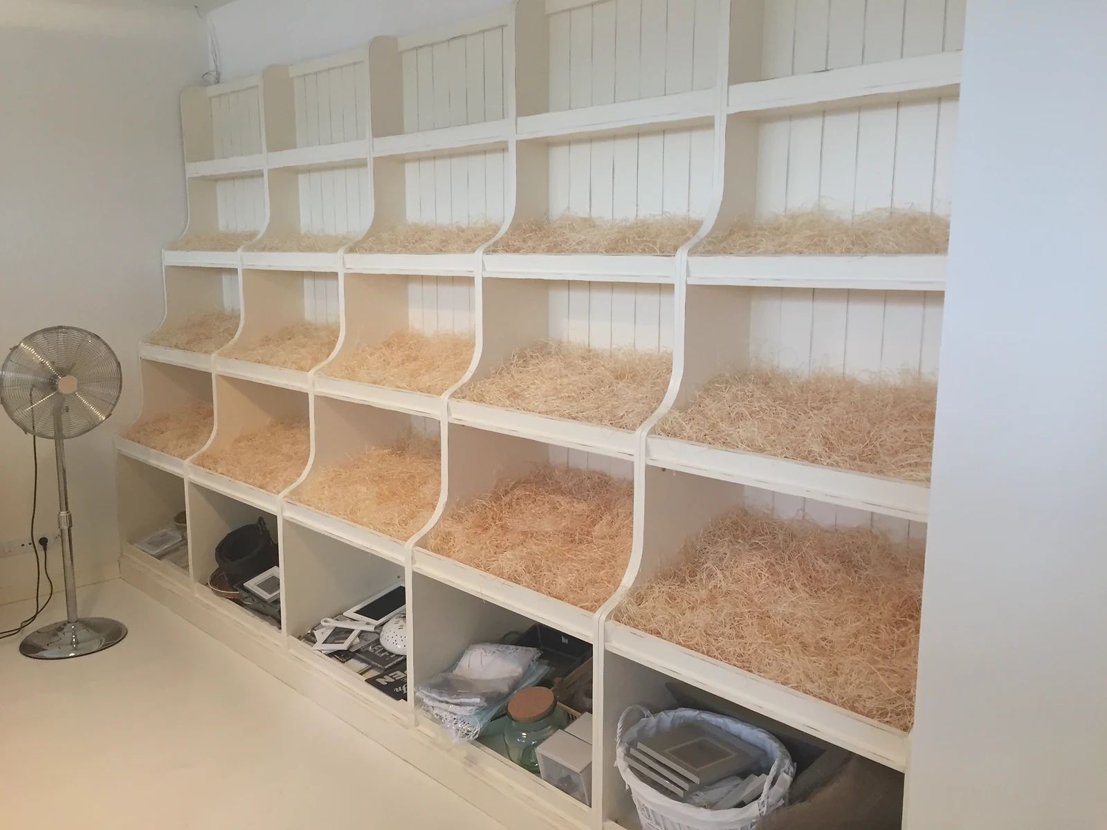 Regál se šikmými přihrádkami vystlanými hoblinami, dole otevřené boxy