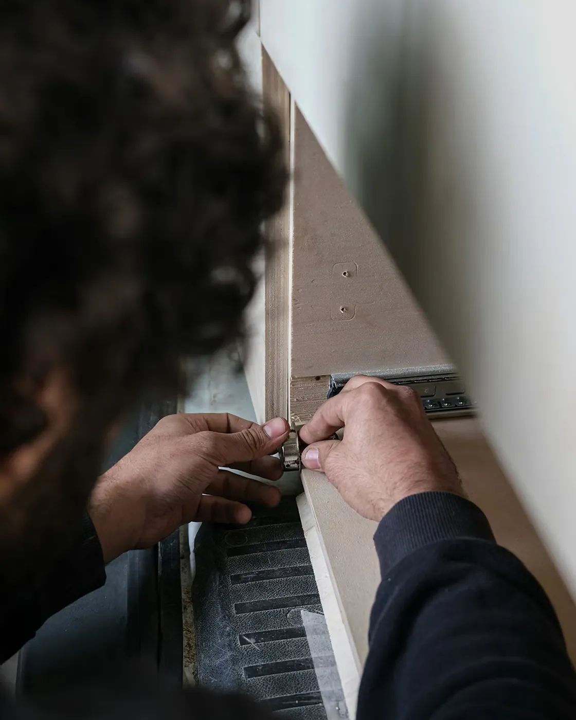 Truhlář zasazuje výsuv do boku skříňky při montáži u zákazníka